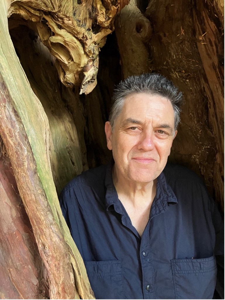 Paul smiles as he stands in the alcove of a great gnarled tree